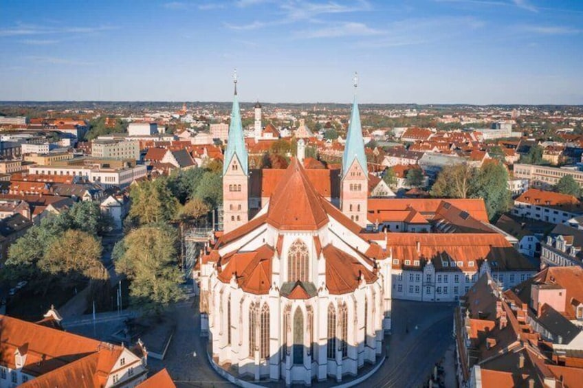 A cathedral with two spires, surrounded by a town with red-roofed buildings. 2