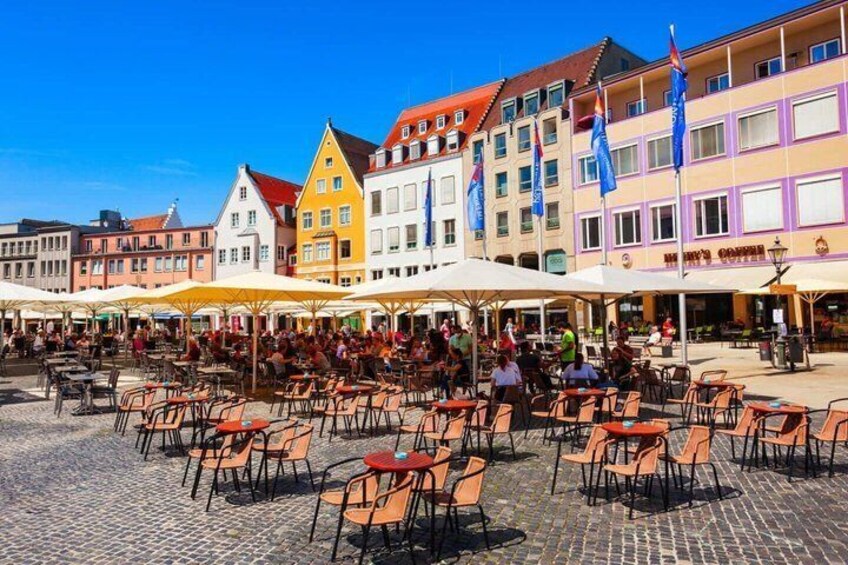 A cobblestone square with outdoor seating and colorful buildings. 4