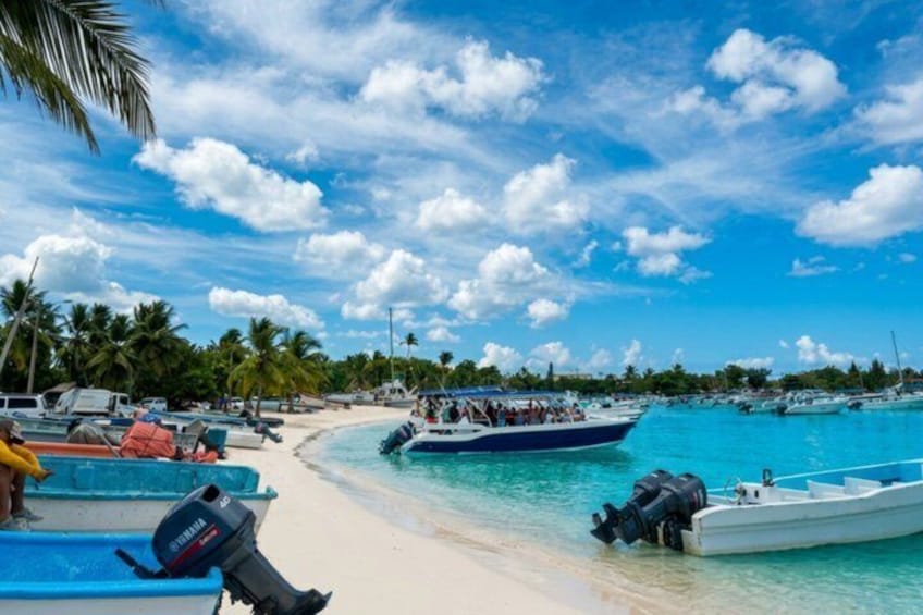 A beach with boats, palm trees, and clear blue water. 1