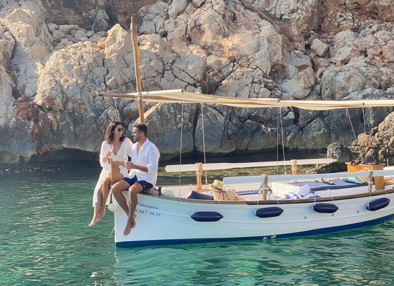 A couple on a boat with a rocky coastline in the background. 1