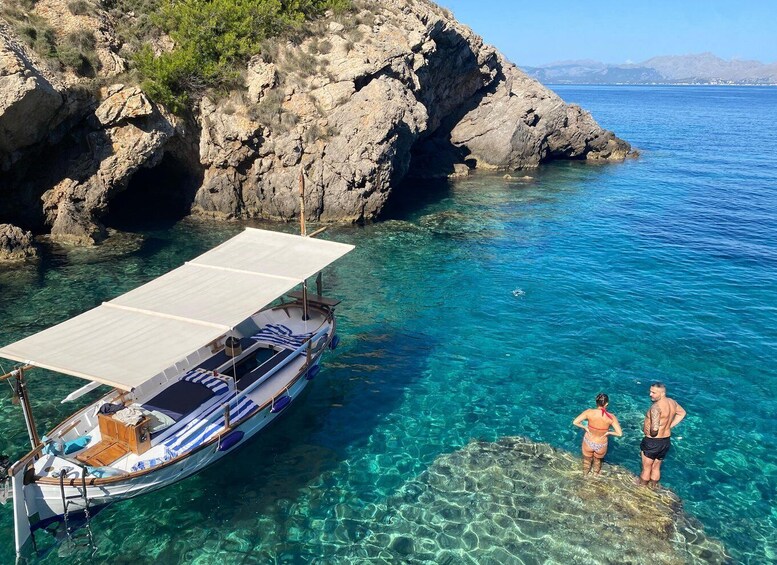 A boat anchored near rocky cliffs with clear blue water. 4