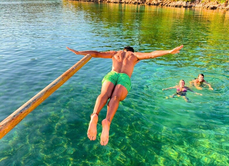 A person jumping off a wooden dock into clear water. 3