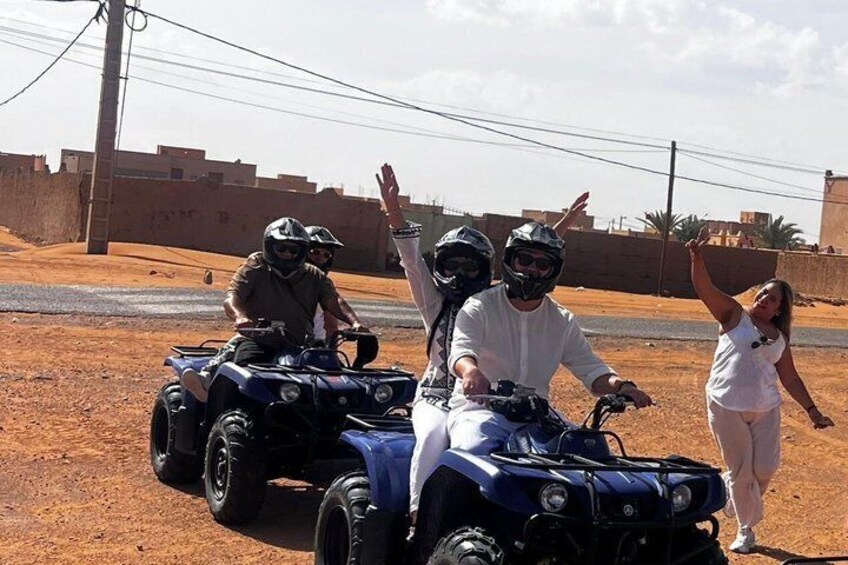 Two quad bikes, a desert landscape, and a person waving. 2