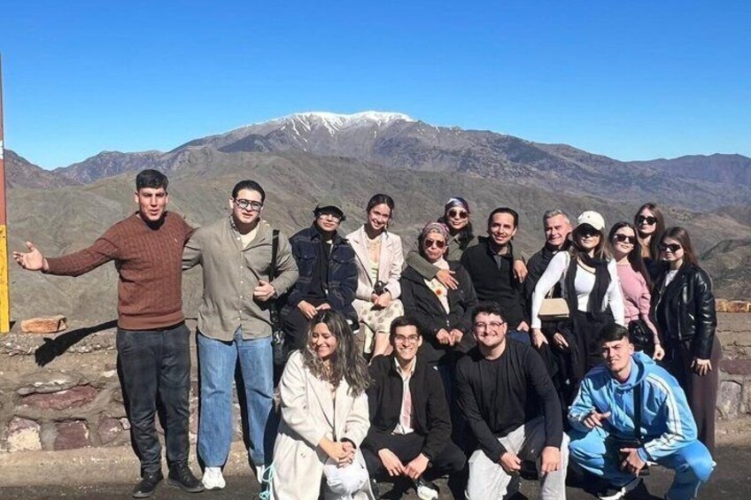 A group of people posing in front of a mountainous landscape with snow-capped peaks. 4