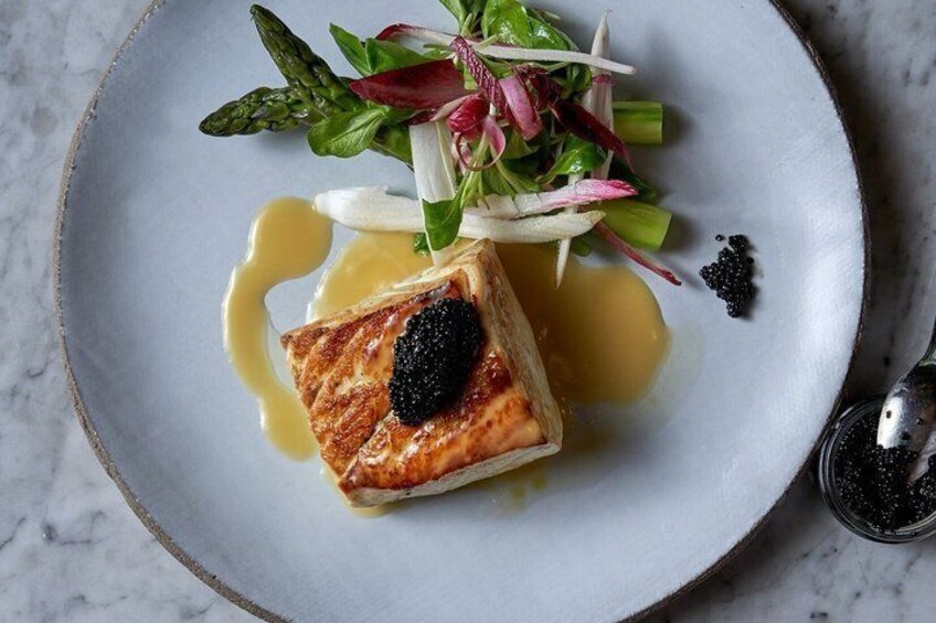 A plate with a piece of grilled fish, asparagus, and a small salad. 5