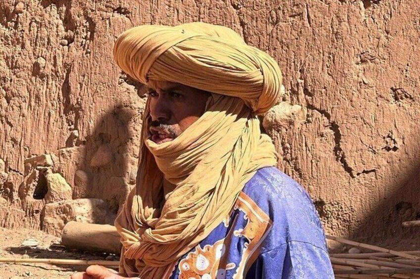 Une personne vêtue d’un costume traditionnel, debout devant un paysage rocheux. 3