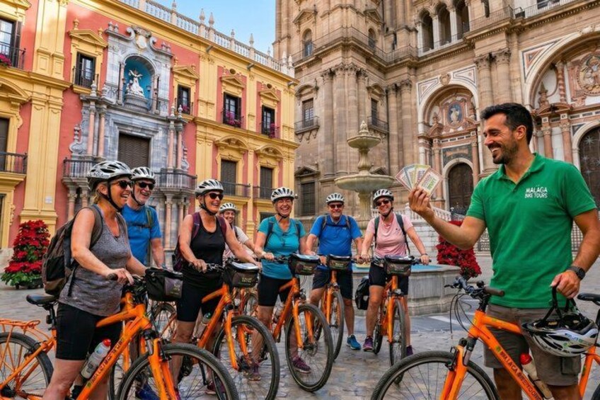 A group of cyclists in a historic plaza with ornate buildings. 2