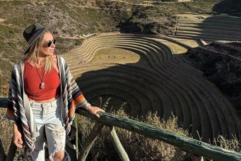 A person standing on a wooden railing overlooking terraced fields. 2