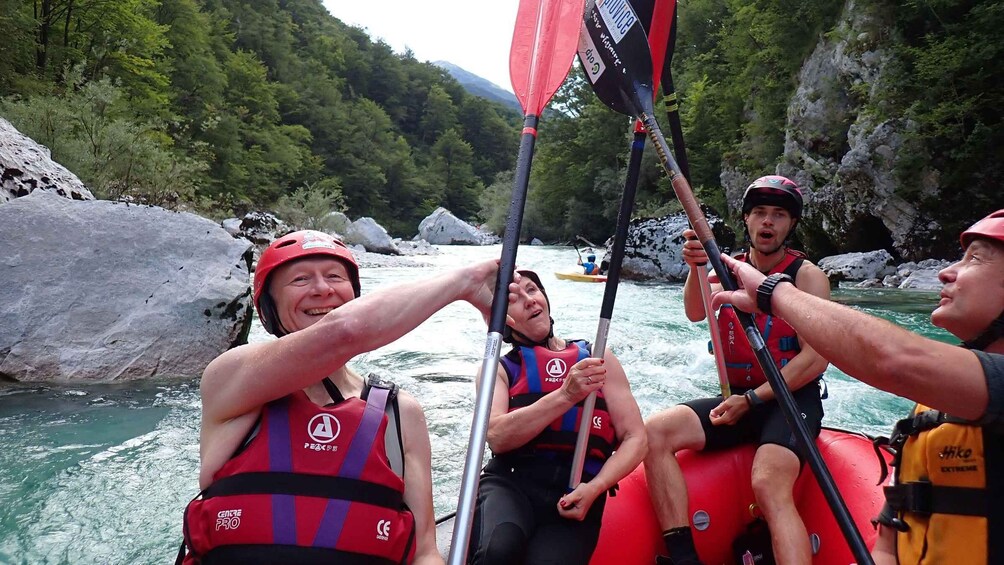 A group of people rafting on a river surrounded by rocky cliffs and greenery. 1