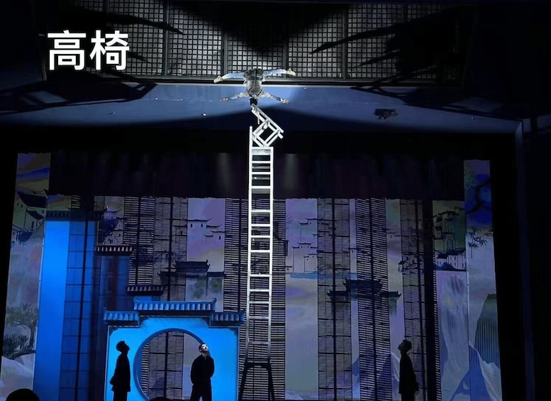 A stage with a blue-lit backdrop, a ladder, and silhouettes of people. 2