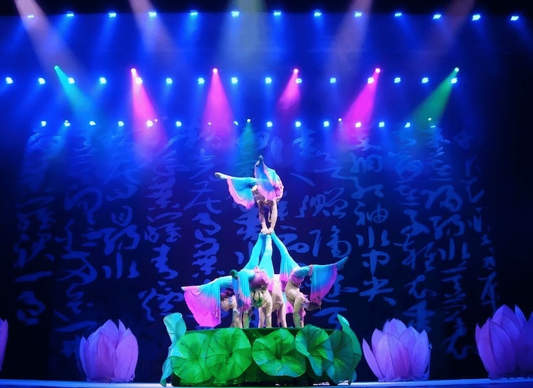 A stage with performers in costumes, a backdrop with Chinese characters, and lotus flowers at the base. 3