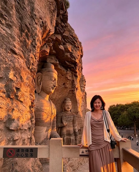 A person standing in front of a rock formation with carved Buddha statues. 2