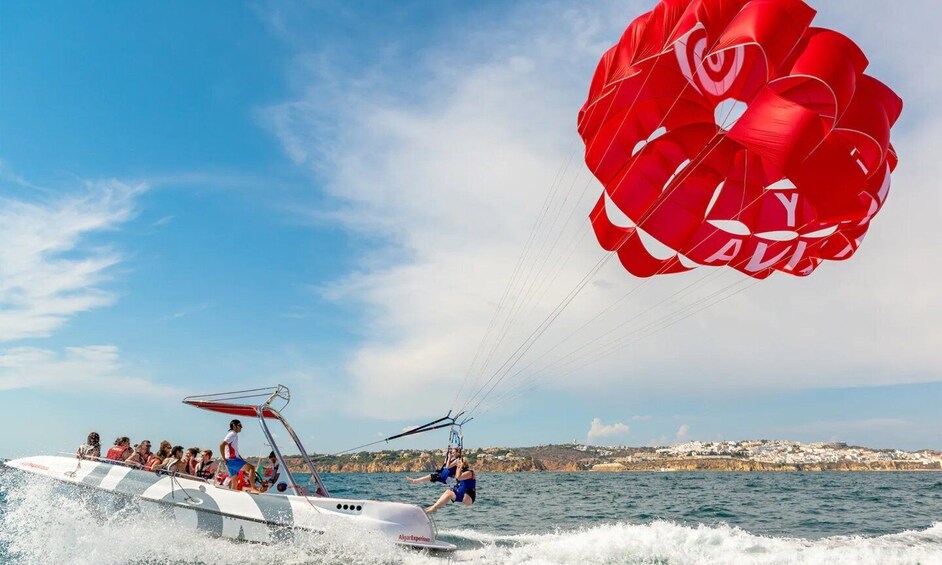 A parasailing activity with a red parachute, a boat, and a coastal landscape. 3