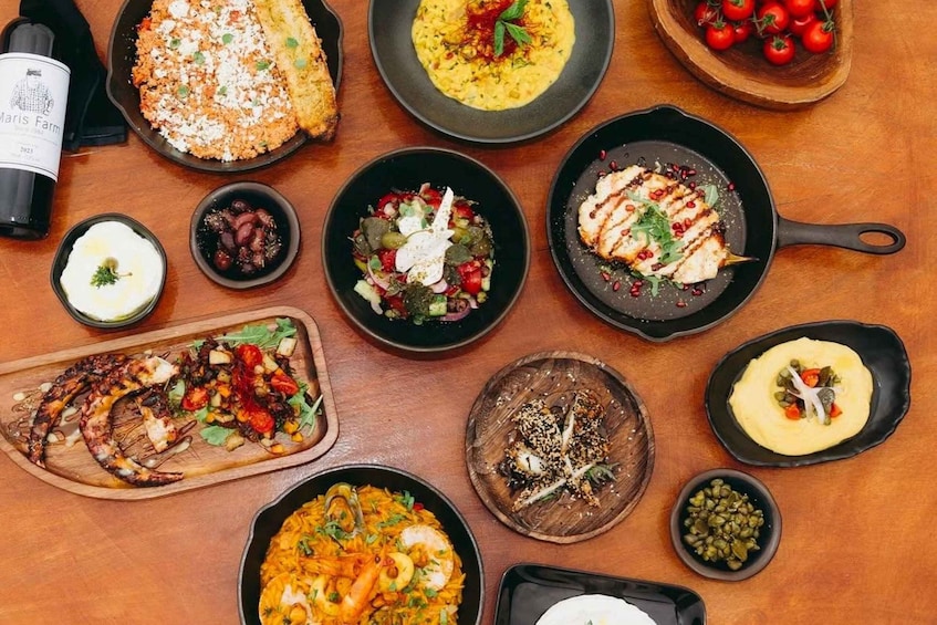 A variety of dishes including seafood, salads, and a bottle of wine on a wooden table. 1