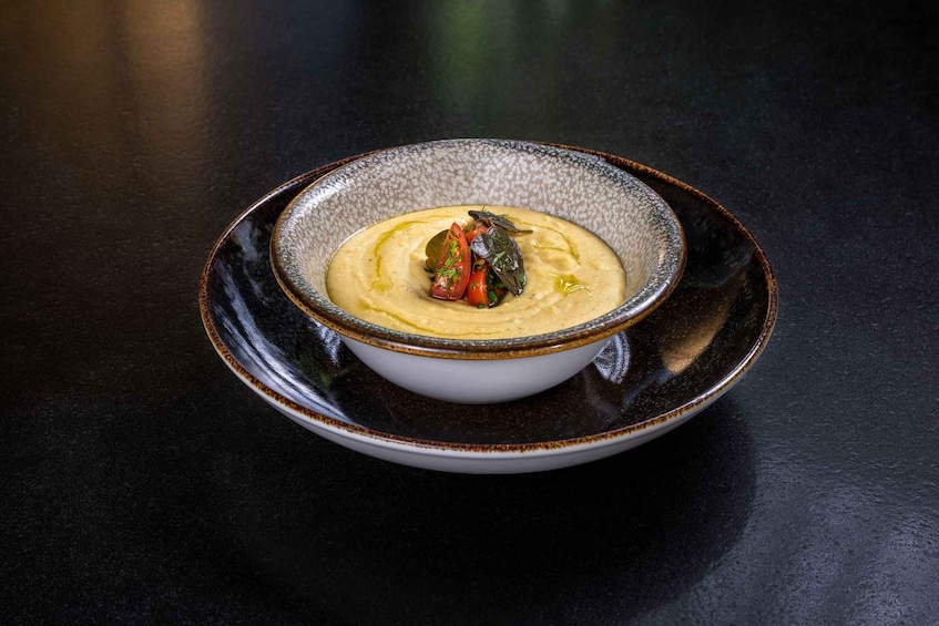 A bowl of soup with vegetables on a dark table. 3