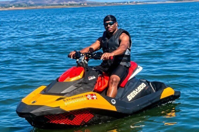 A person riding a yellow and black Sea-Doo jet ski on a body of water. 1