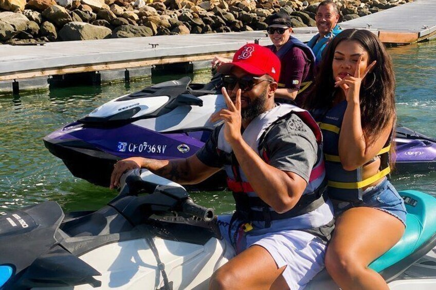 A jet ski with a person and a woman on it, near a dock. 5
