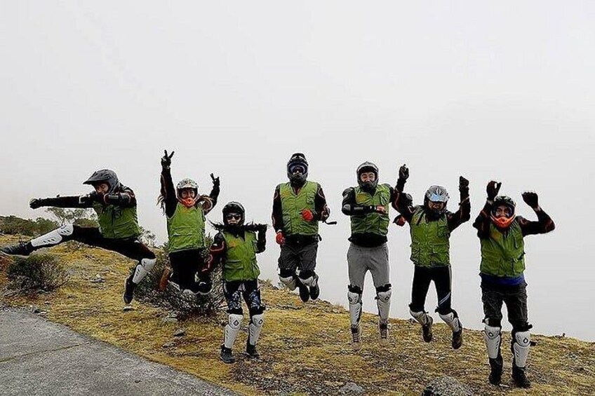 A group of people in green vests and helmets jumping on a grassy hill. 2