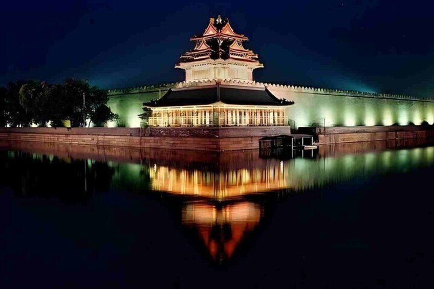 A traditional building with a multi-tiered roof, illuminated by lights, reflecting on a calm body of water. 5