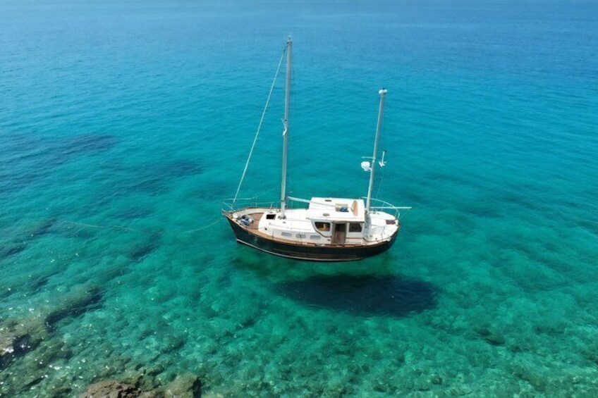 A sailboat floating on clear turquoise water. 1