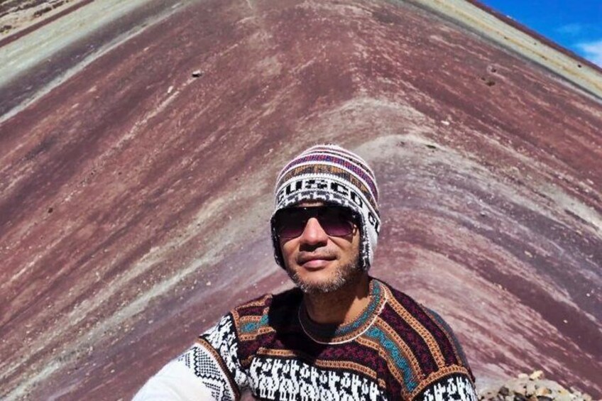 A person taking a selfie with a striped rock formation in the background. 3