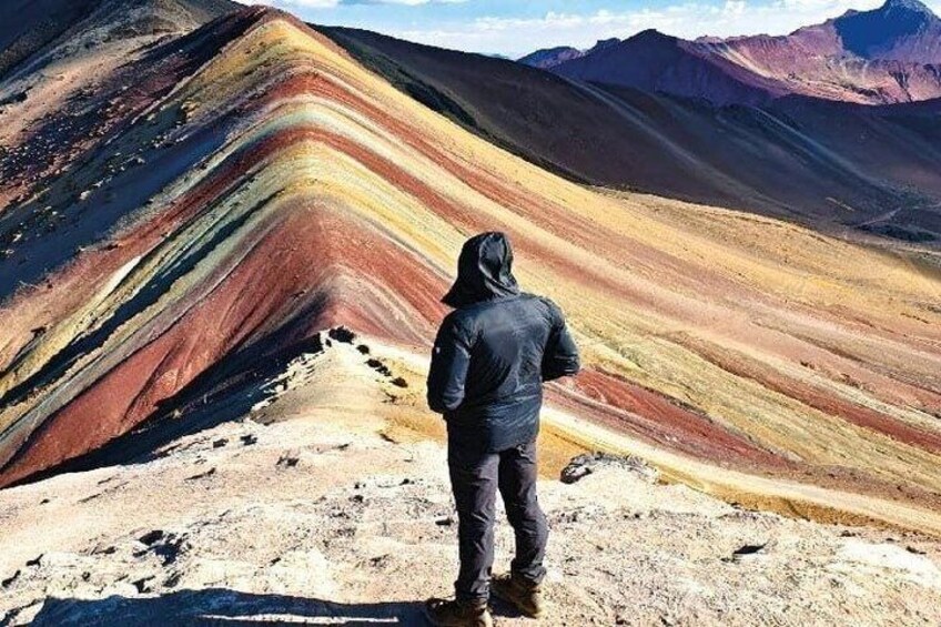 A person standing on a mountain ridge with colorful rock formations. 1
