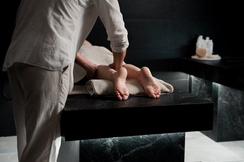 Una persona realiza un masaje en los pies a un cliente sentado en una camilla. 3