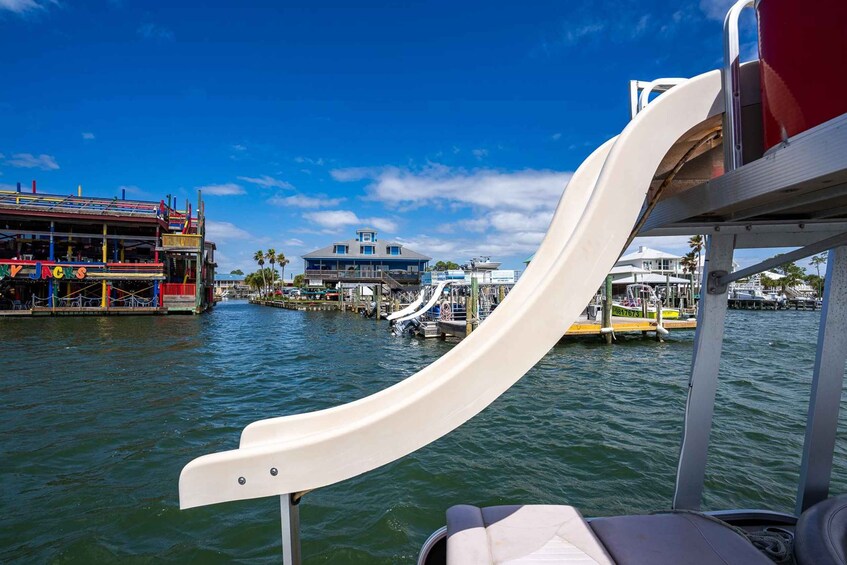 A water slide at a waterfront amusement park with buildings and boats in the background. 4