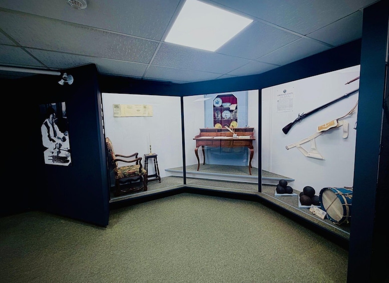 A room with a desk, chair, and various artifacts including a framed picture, a mirror, and a display of historical items. 5