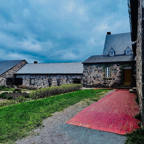 A stone building with a red brick pathway leading to a wooden door. 2