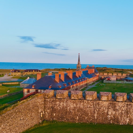 A coastal fort with a prominent tower, surrounded by stone walls and a grassy area. 4