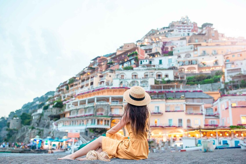 A person sitting on a beach with colorful buildings in the background. 1
