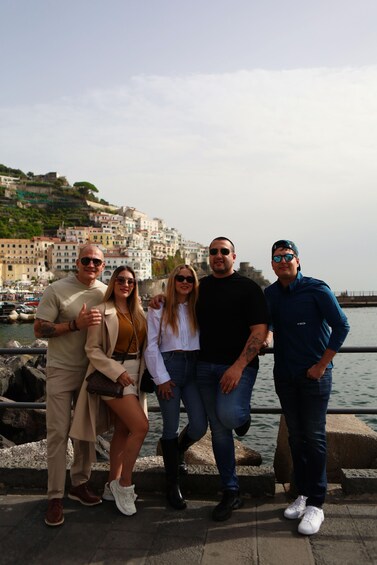 A group of people standing by a waterfront with buildings in the background. 4