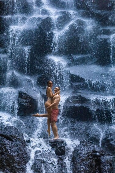 A couple embracing in front of a waterfall. 1
