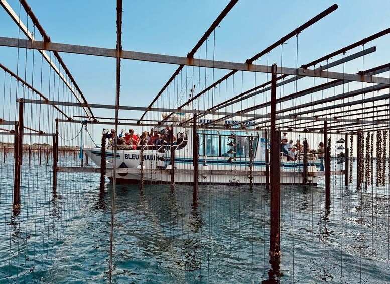 A boat named 'BLEU MARIN' with people on board, surrounded by a metal framework structure in the water. 1