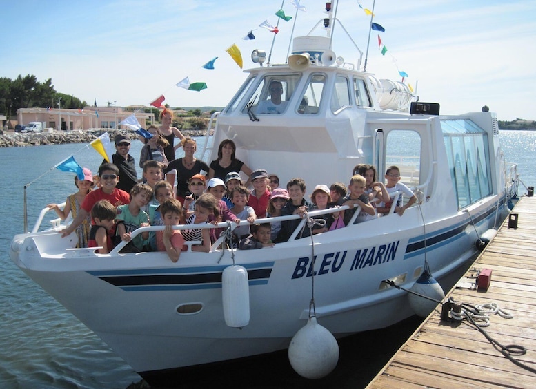 A boat named 'BLEU MARIN' docked at a pier with a group of people on board. 2