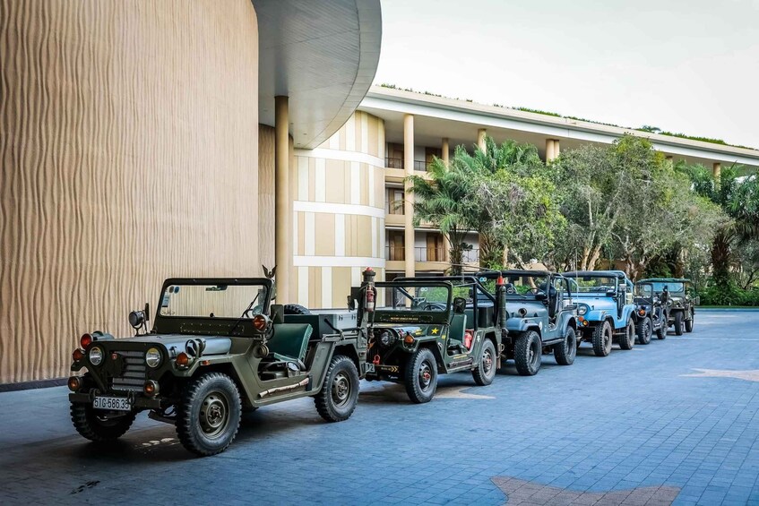 A row of jeeps parked in front of a building with a curved facade and a tiled ground. 4
