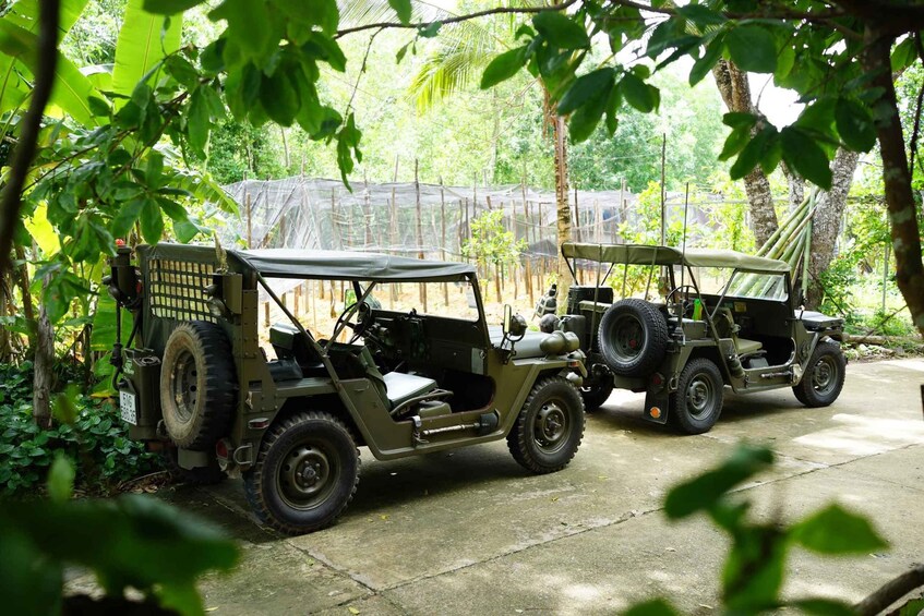Two military jeeps parked on a concrete surface surrounded by greenery. 5