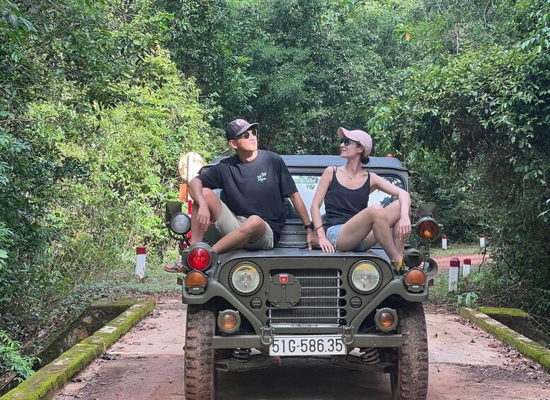 A jeep with two people sitting on the back, surrounded by dense greenery. 1