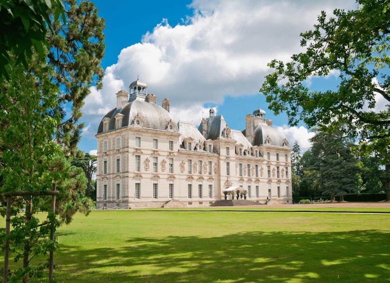 A large, historic building with multiple domes and a well-maintained lawn in front. 1