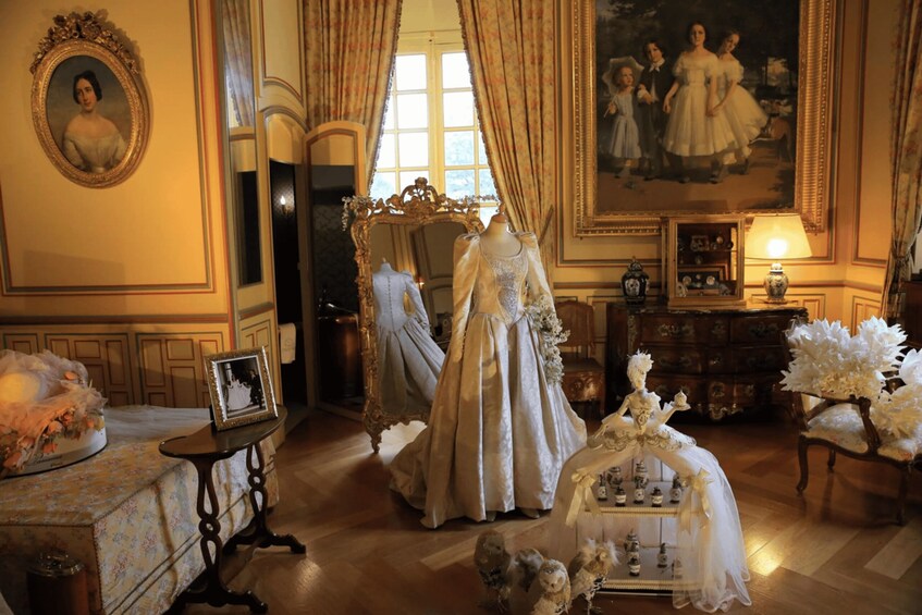 A vintage room with ornate furniture, a mannequin in a dress, and a painting on the wall. 3