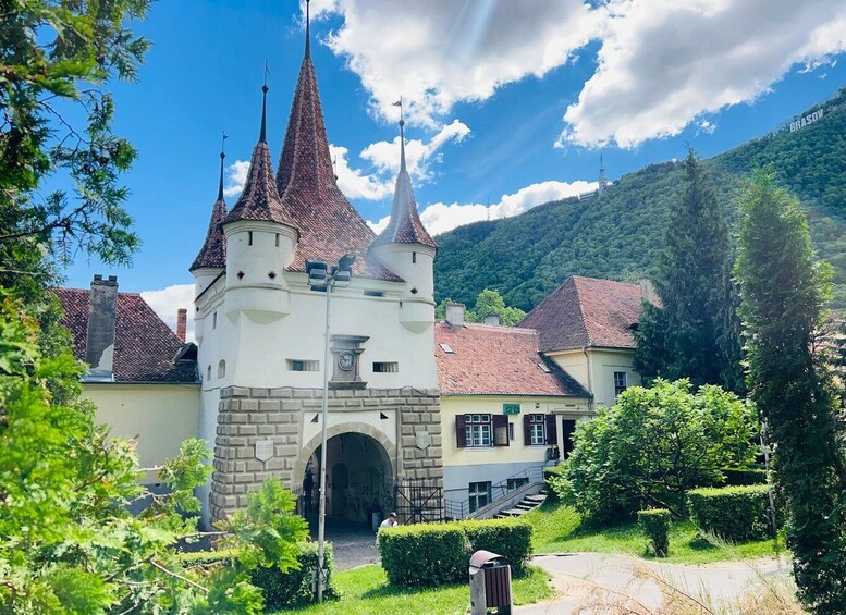 A castle with multiple spires, surrounded by greenery and a clear sky. 1