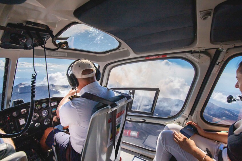 A helicopter cockpit with a pilot and a passenger. 1