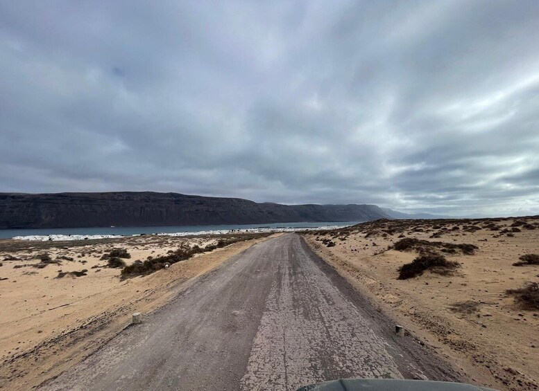A coastal road with a sandy beach and cliffs in the distance. 5