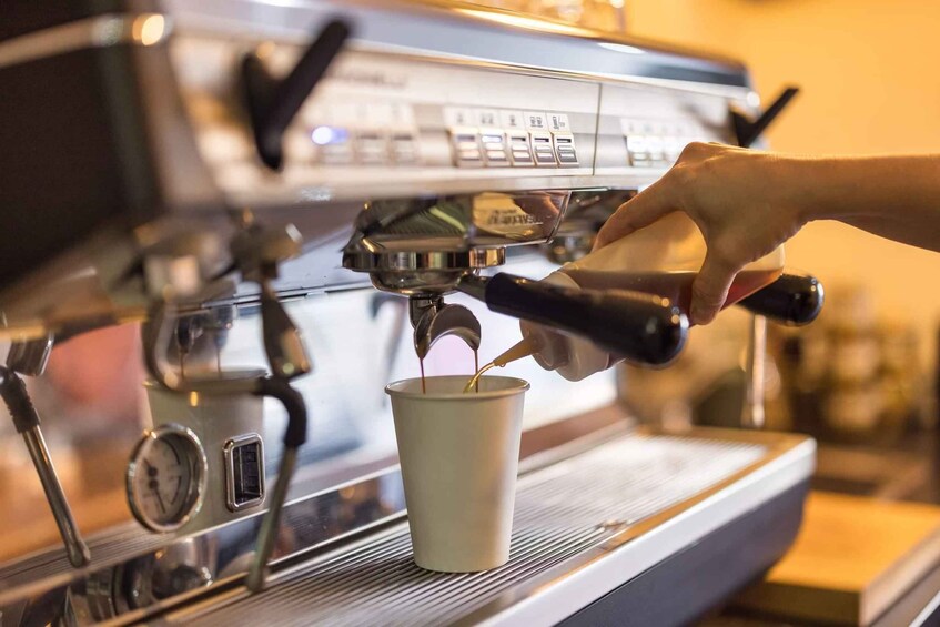 A hand pouring coffee into a cup from an espresso machine. 4