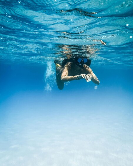 A person swimming underwater in clear blue water. 2