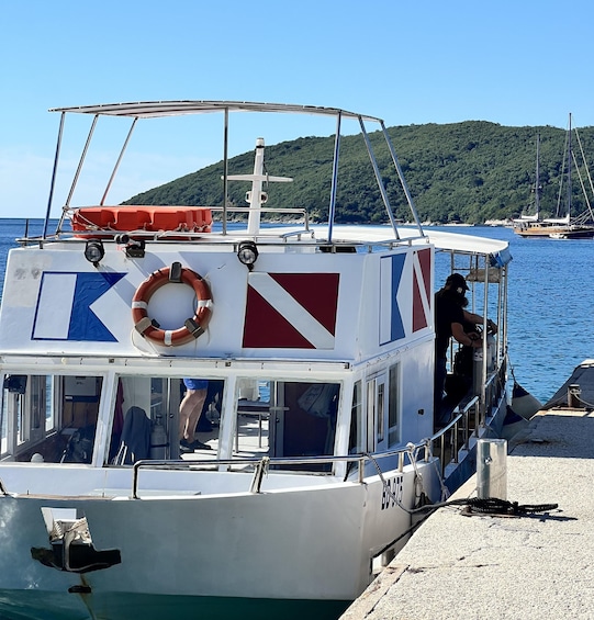 A boat docked at a pier with a lifebuoy, a flag, and a person boarding. 4