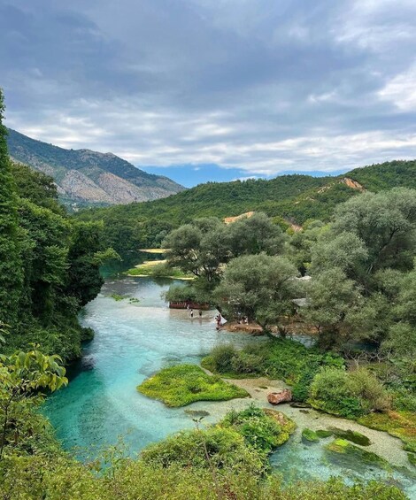 A river flowing through a lush valley with dense greenery and rocky hills in the background. 3