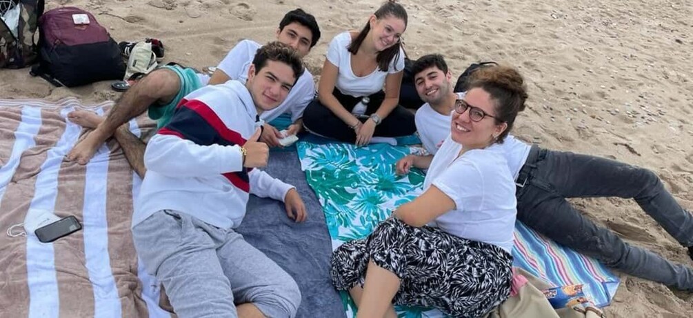 A group of people lying on a beach with a striped blanket and a tropical print blanket. 3