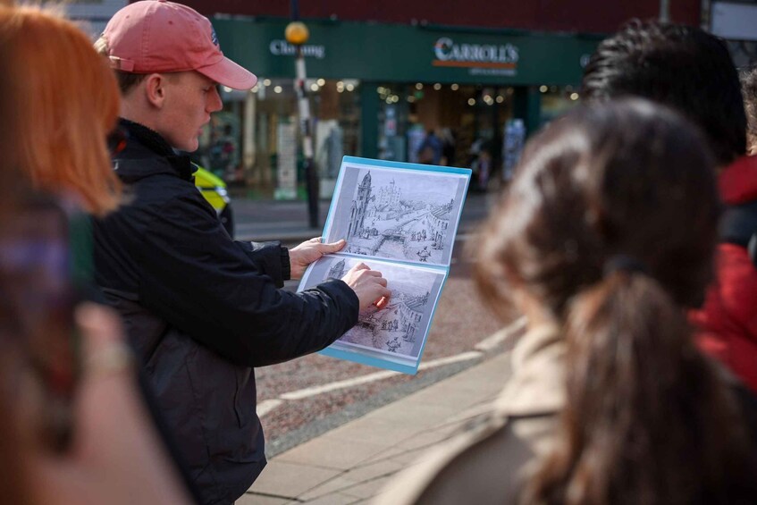 A person holding a booklet with illustrations of a bridge and buildings. 2
